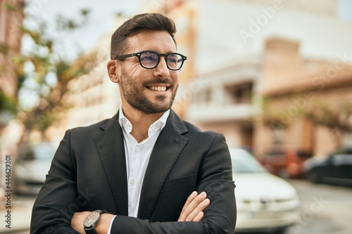 Obraz na plátně Young hispanic businessman with arms crossed smiling happy at the city