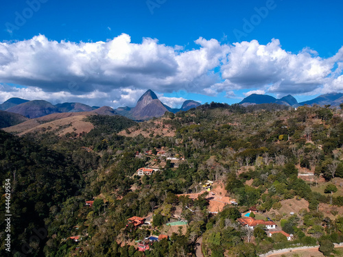 Aerial view of Itaipava  Petr  polis. Mountains with blue sky and some clouds around Petr  polis  mountainous region of Rio de Janeiro  Brazil. Drone photo. Sunny day.