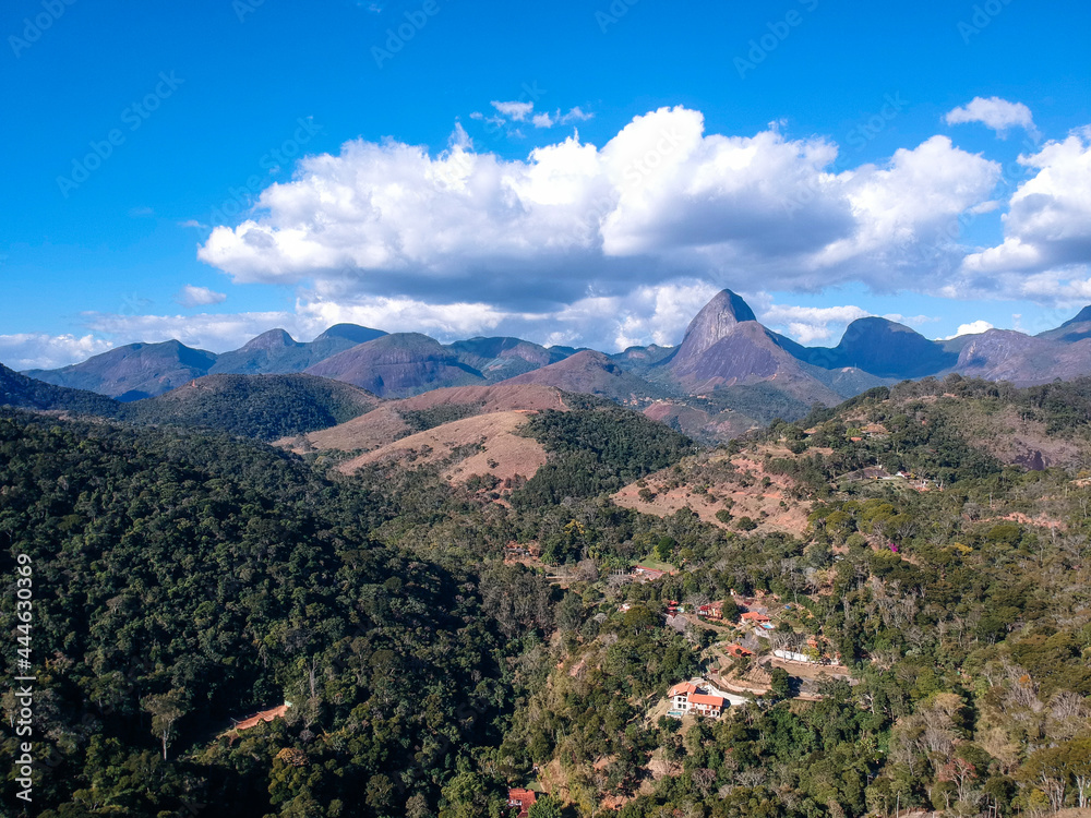 Aerial view of Itaipava, Petrópolis. Mountains with blue sky and some clouds around Petrópolis, mountainous region of Rio de Janeiro, Brazil. Drone photo. Sunny day. Aerial view of Itaipava, Petrópolis. Mountains with blue sky and some clouds around Petrópolis, mountainous region of Rio de Janeiro, Brazil. Drone photo. Sunny day.
