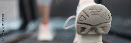 Woman athlete walking on treadmill in gym closeup