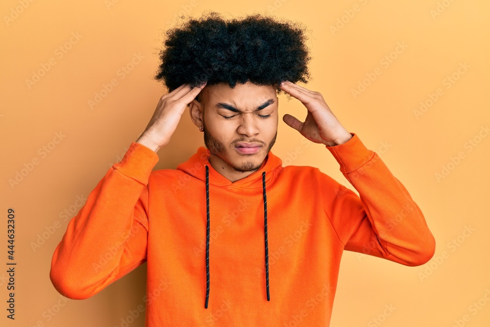 Young african american man with afro hair wearing casual sweatshirt with hand on head, headache because stress. suffering migraine.