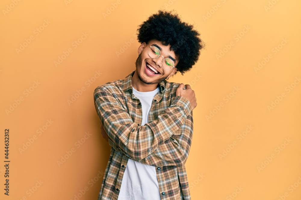 Young african american man with afro hair wearing casual clothes hugging oneself happy and positive, smiling confident. self love and self care Young african american man with afro hair wearing casual clothes hugging oneself happy and positive, smiling confident. self love and self care