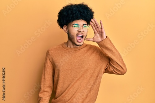 Young african american man with afro hair wearing casual winter sweater shouting and screaming loud to side with hand on mouth. communication concept. © Krakenimages.com