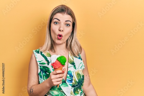 Beautiful caucasian woman eating ice cream scared and amazed with open mouth for surprise, disbelief face