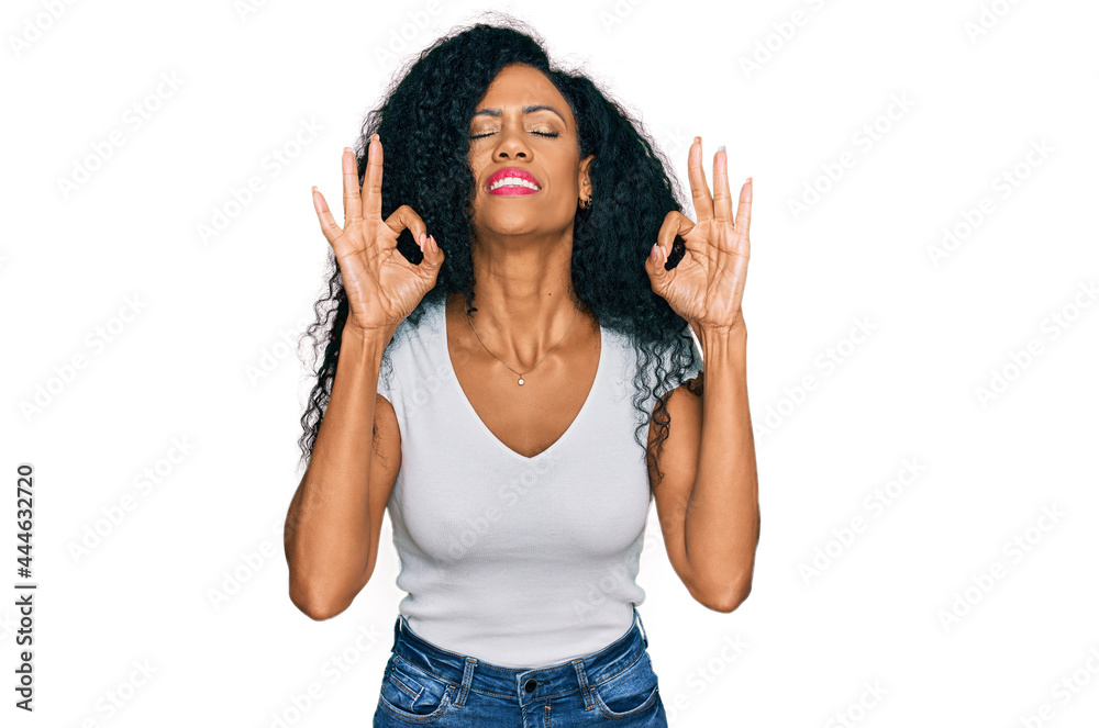 Middle age african american woman wearing casual white t shirt relax and smiling with eyes closed doing meditation gesture with fingers. yoga concept. Middle age african american woman wearing casual white t shirt relax and smiling with eyes closed doing meditation gesture with fingers. yoga concept.