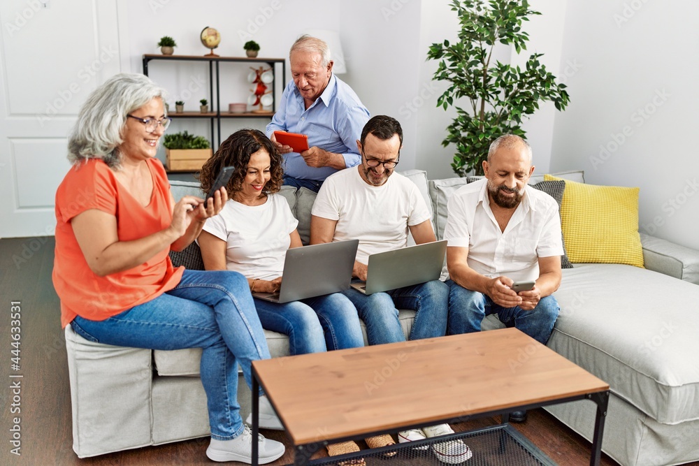 Group of middle age friends using laptop and smartphone sitting on the sofa at home. Group of middle age friends using laptop and smartphone sitting on the sofa at home.