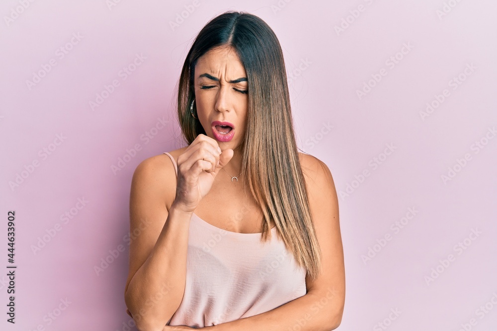 Young hispanic woman wearing casual sleeveless t shirt feeling unwell and coughing as symptom for cold or bronchitis. health care concept. Young hispanic woman wearing casual sleeveless t shirt feeling unwell and coughing as symptom for cold or bronchitis. health care concept.