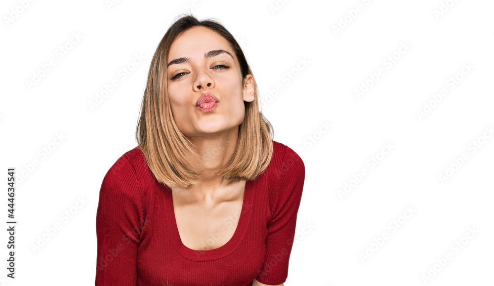 Young blonde girl wearing casual clothes looking at the camera blowing a kiss on air being lovely and sexy. love expression. Young blonde girl wearing casual clothes looking at the camera blowing a kiss on air being lovely and sexy. love expression.
