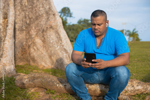 Latin man chatting with his cell phone in the tree photo