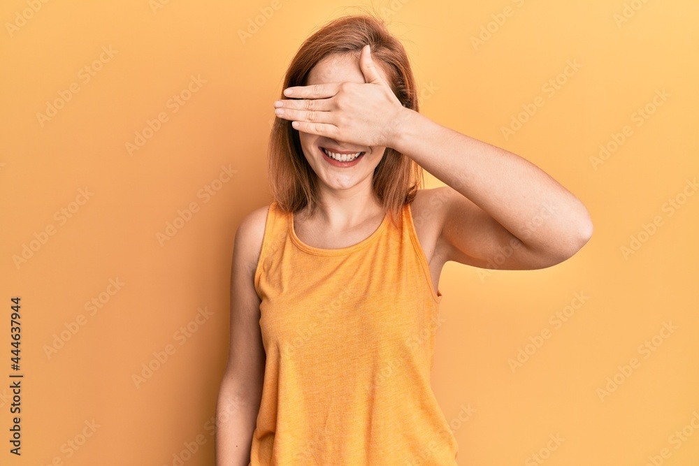 Young caucasian woman wearing casual style with sleeveless shirt smiling and laughing with hand on face covering eyes for surprise. blind concept. Young caucasian woman wearing casual style with sleeveless shirt smiling and laughing with hand on face covering eyes for surprise. blind concept.