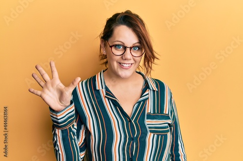 Young caucasian woman wearing casual clothes and glasses showing and pointing up with fingers number five while smiling confident and happy.