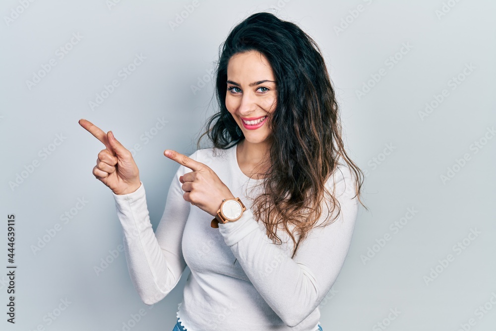 Young hispanic woman wearing casual clothes smiling and looking at the camera pointing with two hands and fingers to the side. Young hispanic woman wearing casual clothes smiling and looking at the camera pointing with two hands and fingers to the side.