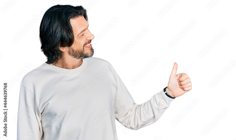 Middle age caucasian man wearing casual clothes looking proud, smiling doing thumbs up gesture to the side Middle age caucasian man wearing casual clothes looking proud, smiling doing thumbs up gesture to the side