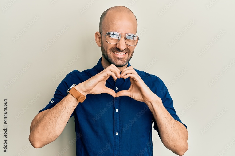 Young hispanic man wearing casual clothes and glasses smiling in love showing heart symbol and shape with hands. romantic concept. Young hispanic man wearing casual clothes and glasses smiling in love showing heart symbol and shape with hands. romantic concept.