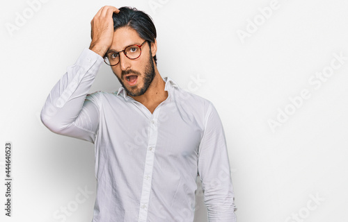 Young hispanic man wearing business shirt and glasses surprised with hand on head for mistake, remember error. forgot, bad memory concept. © Krakenimages.com