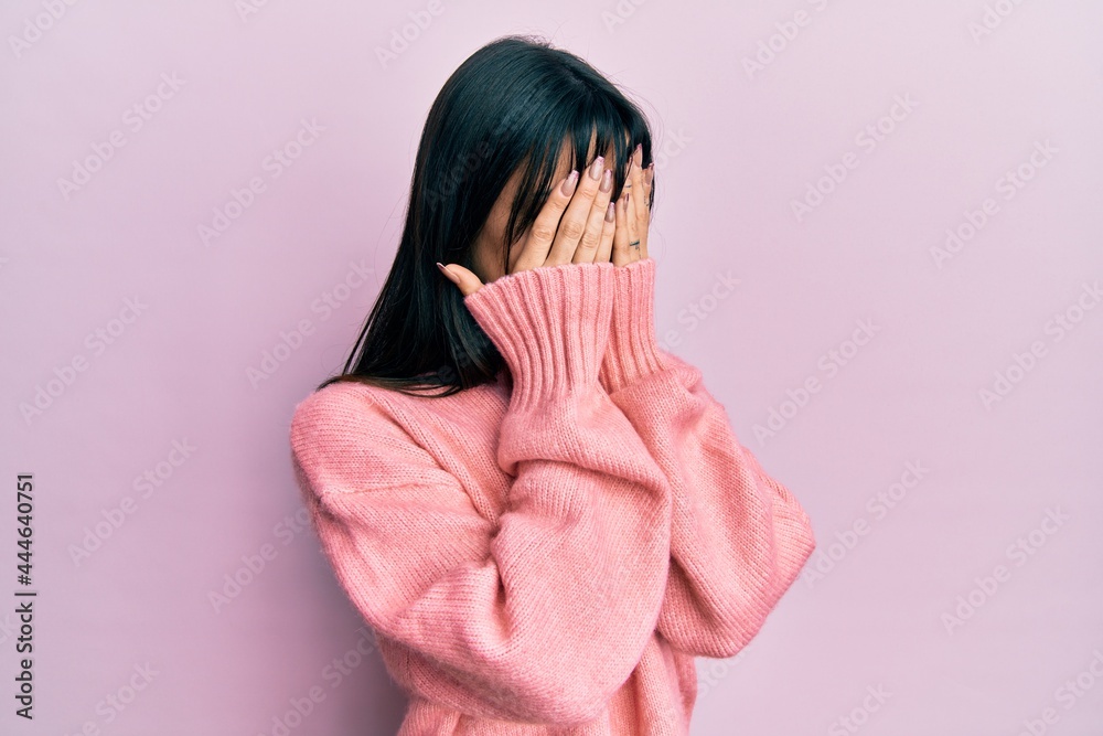 Young brunette woman with bangs wearing casual winter sweater with sad expression covering face with hands while crying. depression concept. Young brunette woman with bangs wearing casual winter sweater with sad expression covering face with hands while crying. depression concept.