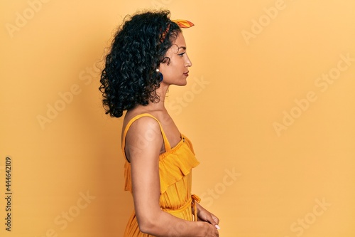 Young latin girl wearing summer dress looking to side, relax profile pose with natural face with confident smile.