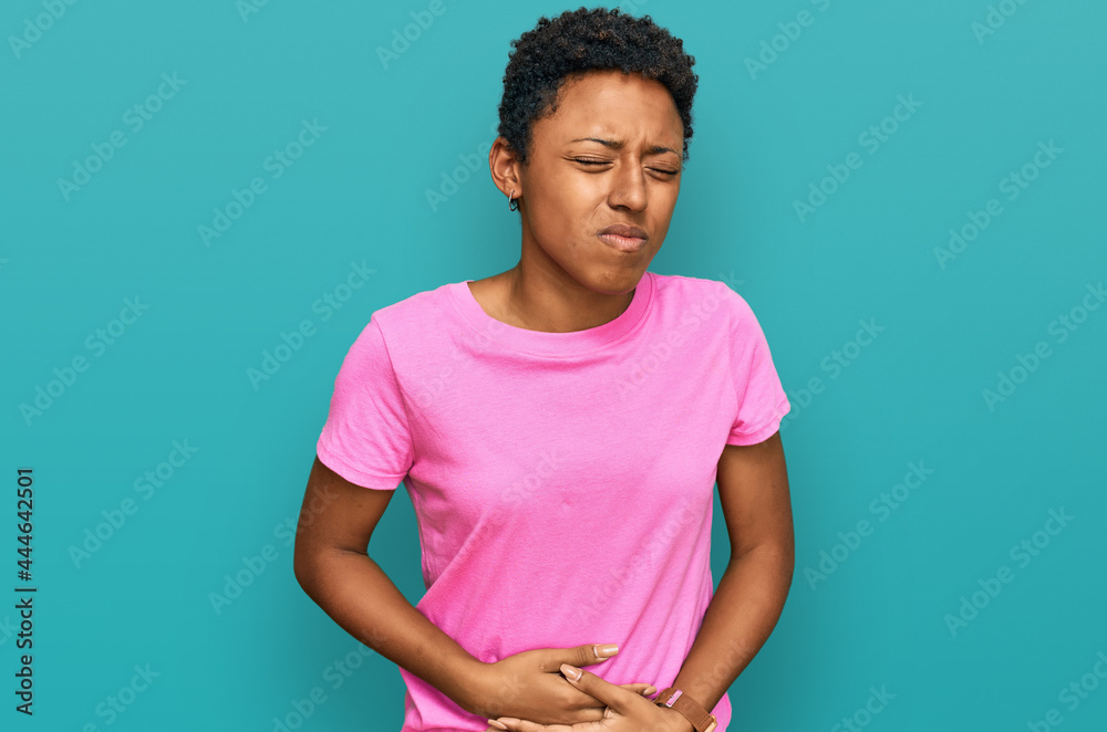 Young african american woman wearing casual clothes with hand on stomach because indigestion, painful illness feeling unwell. ache concept. Young african american woman wearing casual clothes with hand on stomach because indigestion, painful illness feeling unwell. ache concept.