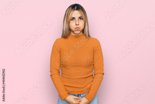 Young caucasian woman wearing casual clothes puffing cheeks with funny face. mouth inflated with air, crazy expression. photo