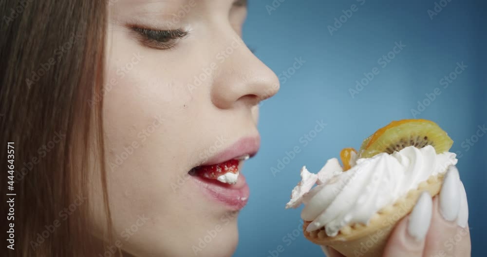 Portrait of young woman eating delicious sweet cake, looking in camera with pleased face. Close-up of female student with green eyes. Happy hungry model tasting cheesecake in studio. Portrait of young woman eating delicious sweet cake, looking in camera with pleased face. Close-up of female student with green eyes. Happy hungry model tasting cheesecake in studio.