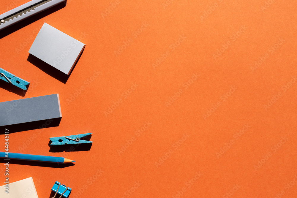 Blue memo notepad, clips, cutter, colored pencil on red background. Work and study place. flat lay, top view, copy space Blue memo notepad, clips, cutter, colored pencil on red background. Work and study place. flat lay, top view, copy space