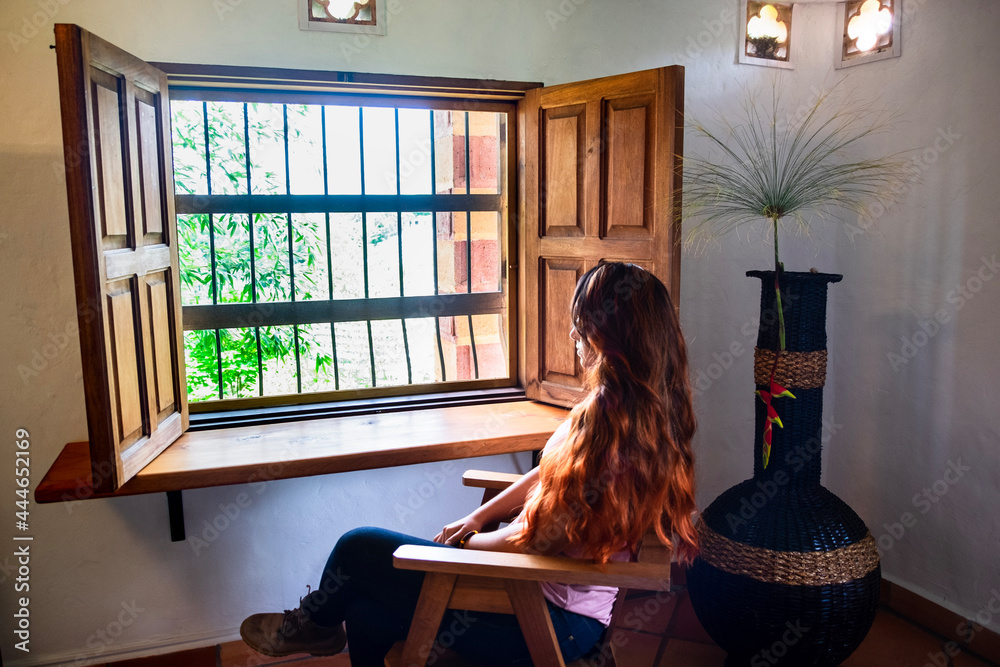 ed haired woman looking through a wooden window