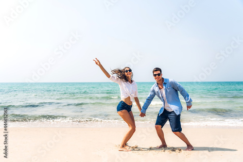 Vacation romantic lovers young happy couple holding hands walking on sand by sea having fun and relaxing together on tropical beach.Summer vacations and travel