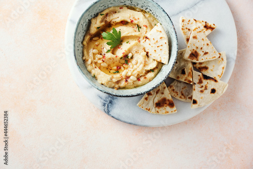 Homemade hummus with pine nuts and pita slices.