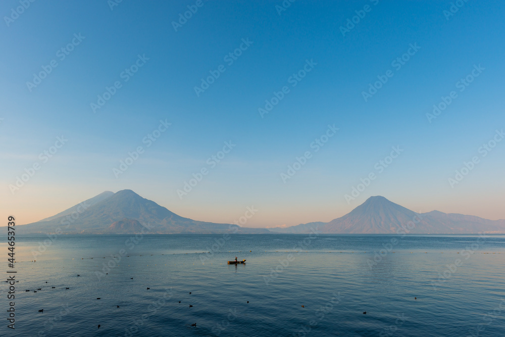 Atitlan Lake with Toliman, San Pedro and Atitlan volcano at sunrise and fisherman, Panajachel, Guatemala.