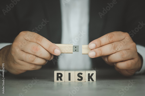 Businessman holds usb flash drive in his hand and word text RISK wood block.