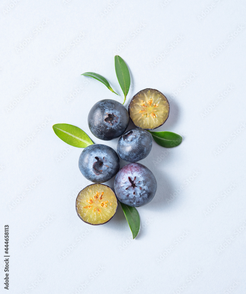 Concept flat lay with a few juicy blueberries with green leaves on blue background. Top view and copy space Concept flat lay with a few juicy blueberries with green leaves on blue background. Top view and copy space