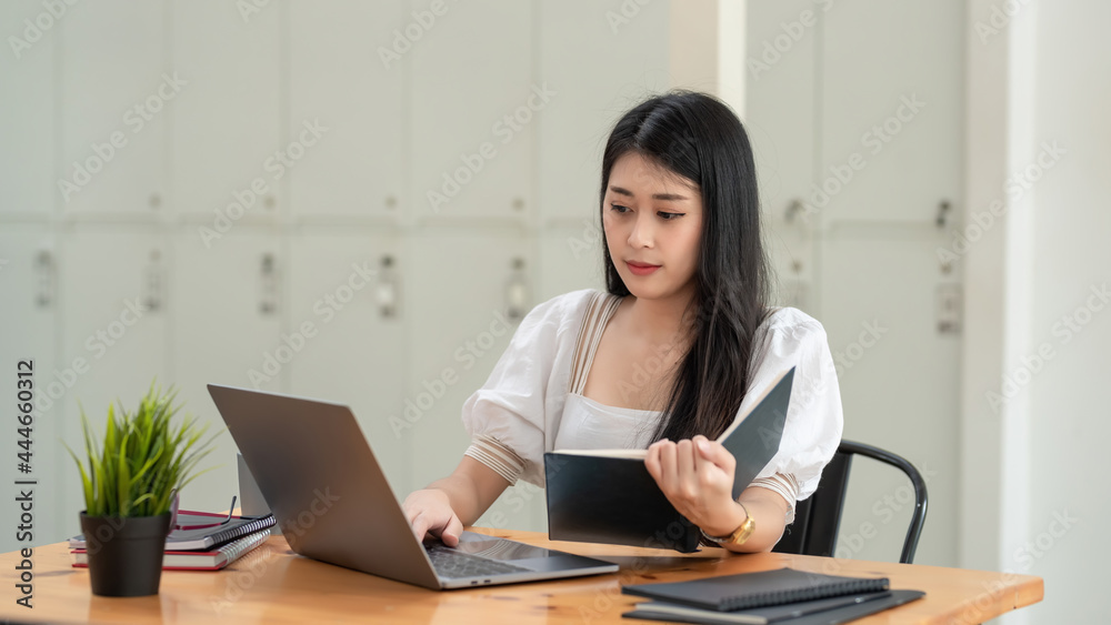 Perspective working Asian businesswoman using laptop and holding documents at office. Perspective working Asian businesswoman using laptop and holding documents at office.