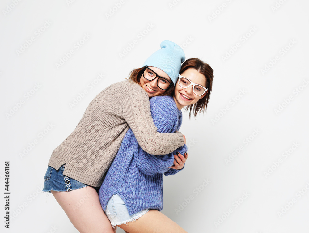 lifestyle, people and friendship concept: Two young female friends standing and hugging together lifestyle, people and friendship concept: Two young female friends standing and hugging together