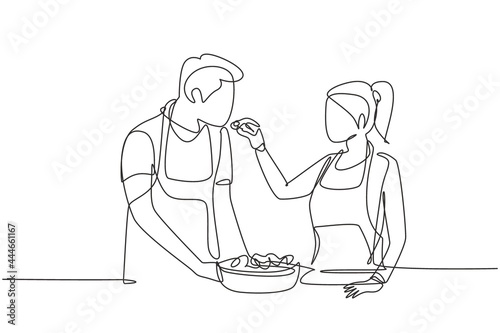 Continuous one line drawing beautiful wife feeds her husband food and in front of him is bowl filled with salad. Cooking together in cozy kitchen. Single line draw design vector graphic illustration