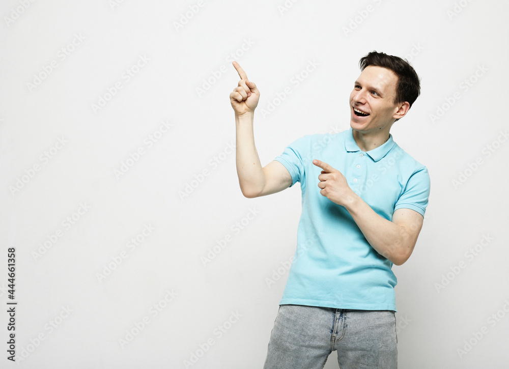 Portrait with copyspace, cute smiling man indicate showing empty place with two forefingers Portrait with copyspace, cute smiling man indicate showing empty place with two forefingers