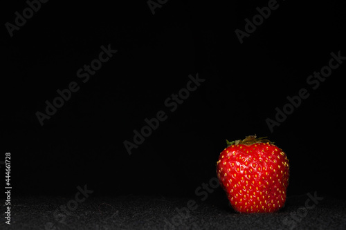 One strawberry on a dark background