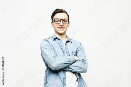 Portrait of happy fashionable handsome man wearing glasses in jeans shirt crossing hands and look at camera © Raisa Kanareva