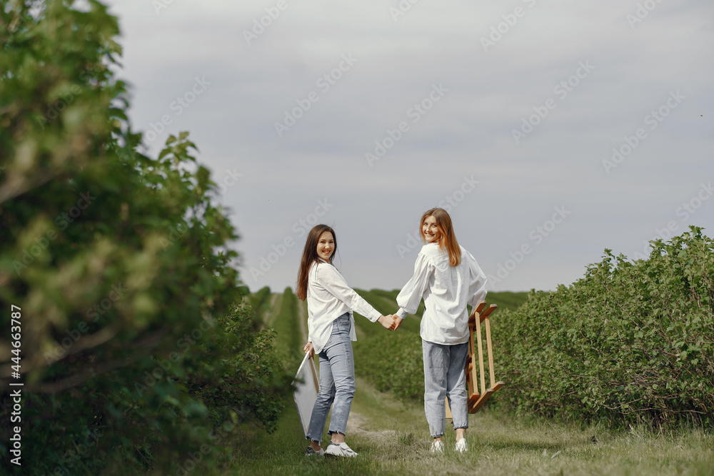 Elegant and beautiful girls painting in a field Elegant and beautiful girls painting in a field