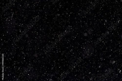 Night sky with brightly shining stars, white snow on black background