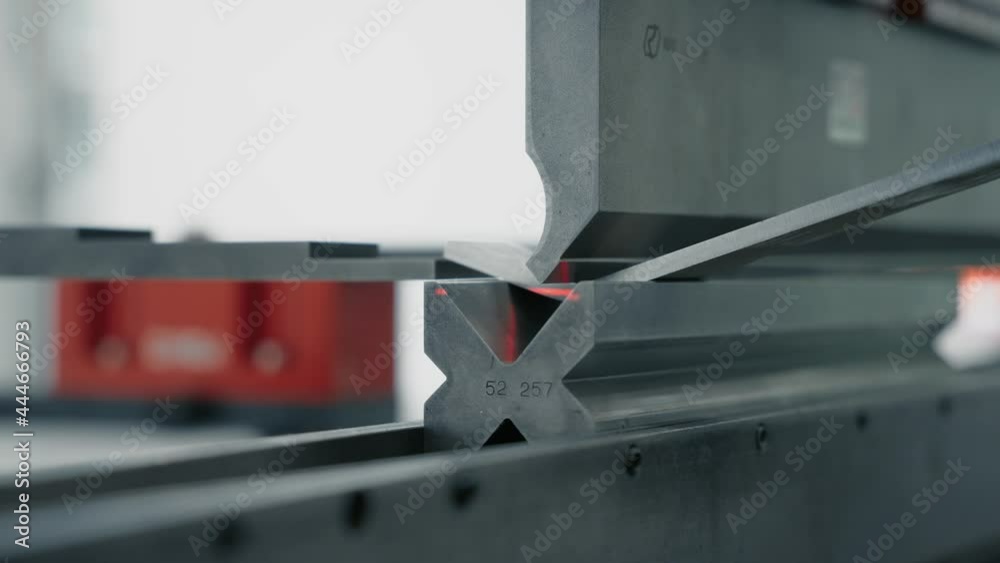 Press brake is bending stainless steel. Close up side view. Press brake is bending stainless steel. Close up side view.