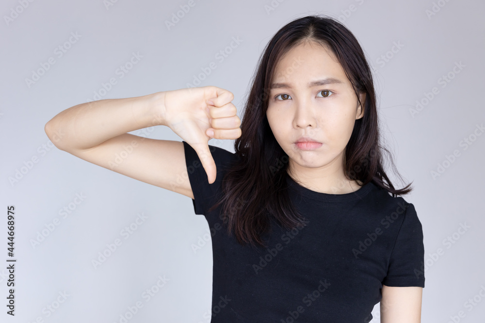 woman saying no with rejecting thumb down gesture and negative facial expression woman saying no with rejecting thumb down gesture and negative facial expression