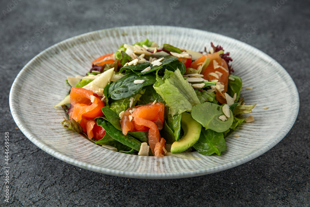 Hearty dietary salad made from salmon, avocado, herbs and sauce. Ready menu for the restaurant. Neutral gray blue textured background