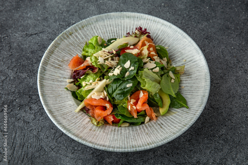 Hearty dietary salad made from salmon, avocado, herbs and sauce. Ready menu for the restaurant. Neutral gray blue textured background Hearty dietary salad made from salmon, avocado, herbs and sauce. Ready menu for the restaurant. Neutral gray blue textured background