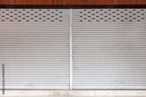 The silver roller shutter door of the store is closed