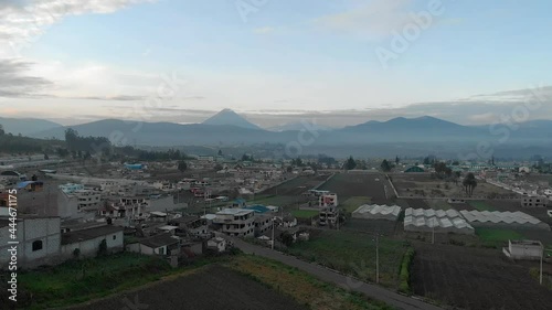 Town and volcano during sunrise in Andes of Ecuacor. Volcano Tungurahuaand Andean Peaks. High Altitude Drone Shot Of Ambato, Ecuador photo