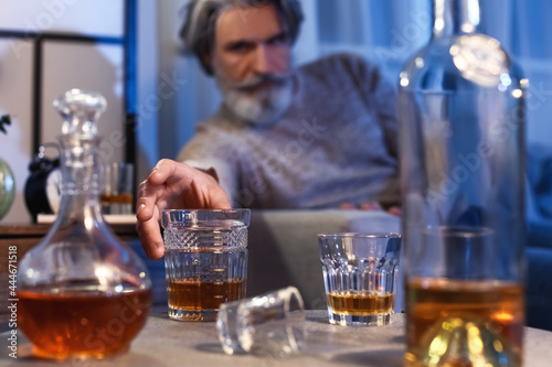 Senior man with glass of drink late in evening at home, closeup