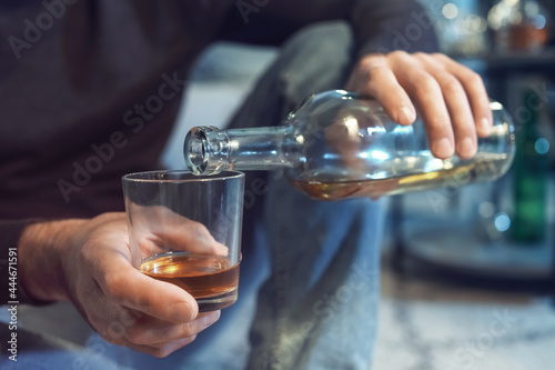 Senior man pouring drink into glass late in evening at home  closeup