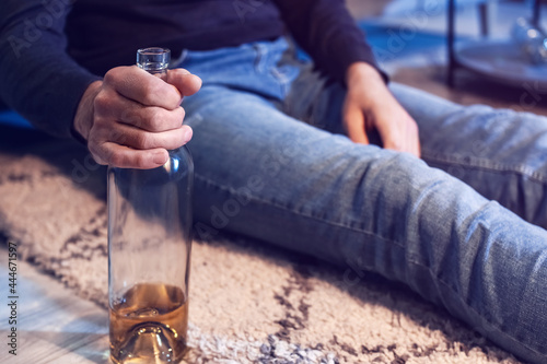 Senior man with bottle of drink late in evening at home, closeup