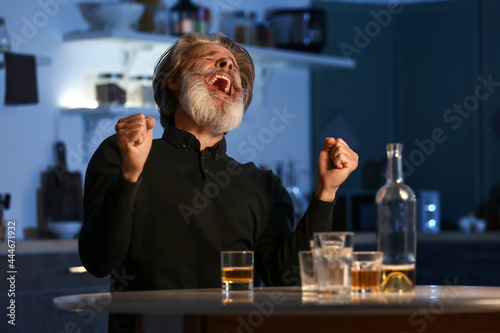 Angry senior man in kitchen at night