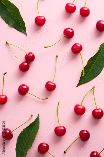 Cherry pattern. Flat lay cherries and leaves on pink background. Top view